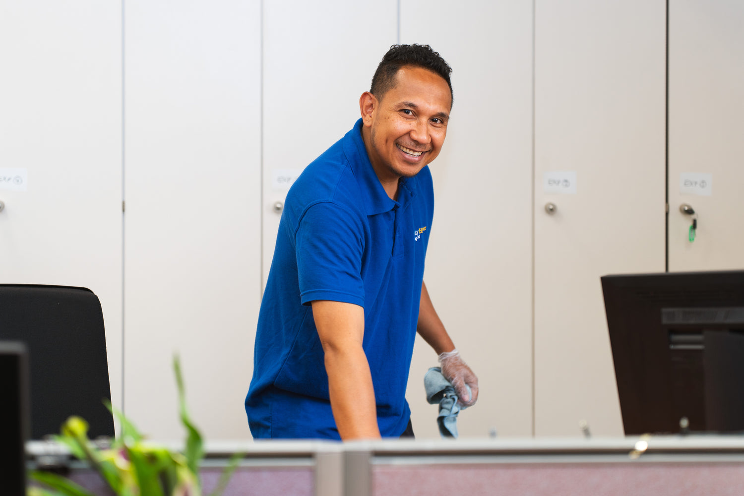 Man in a blue shirt cleaning a desk in an office setting